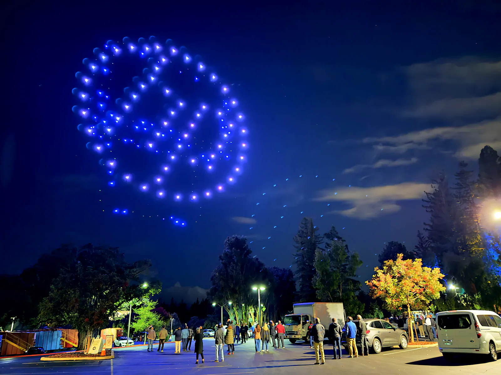 Drone light show forming an abstract globe above the crowd at an evening tour stop