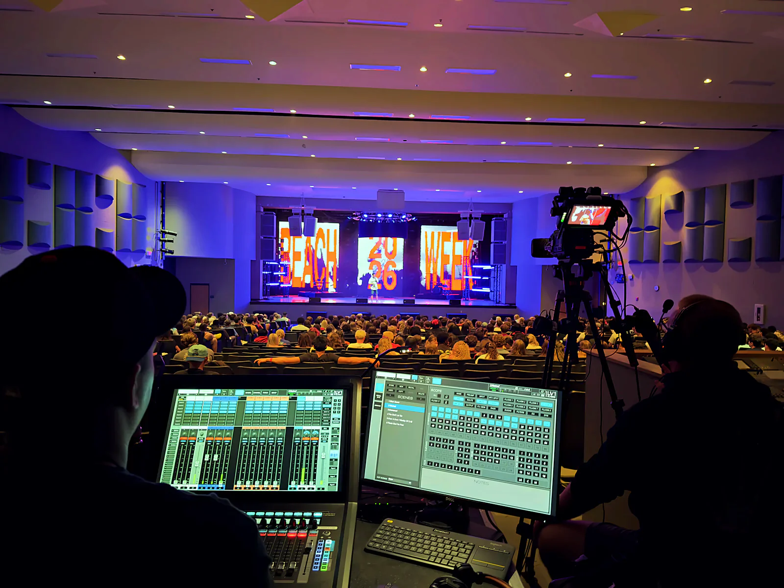 Front-of-house position: digital audio console and mix screens with the full house and lit stage beyond
