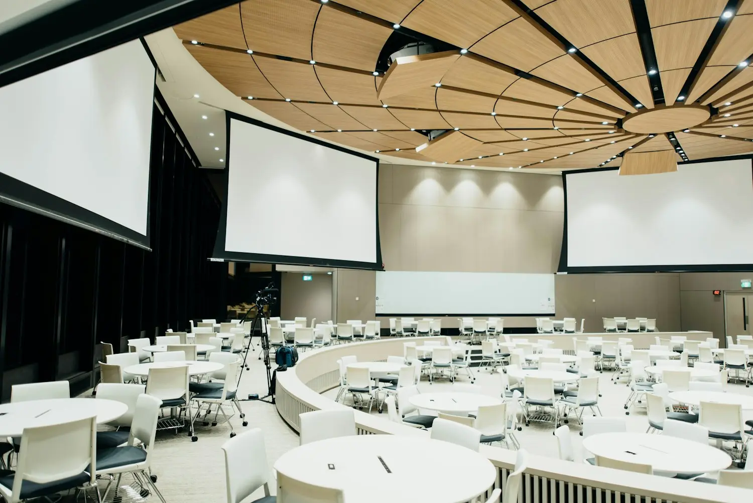 Round-table conference hall with projection screens set for a corporate summit general session