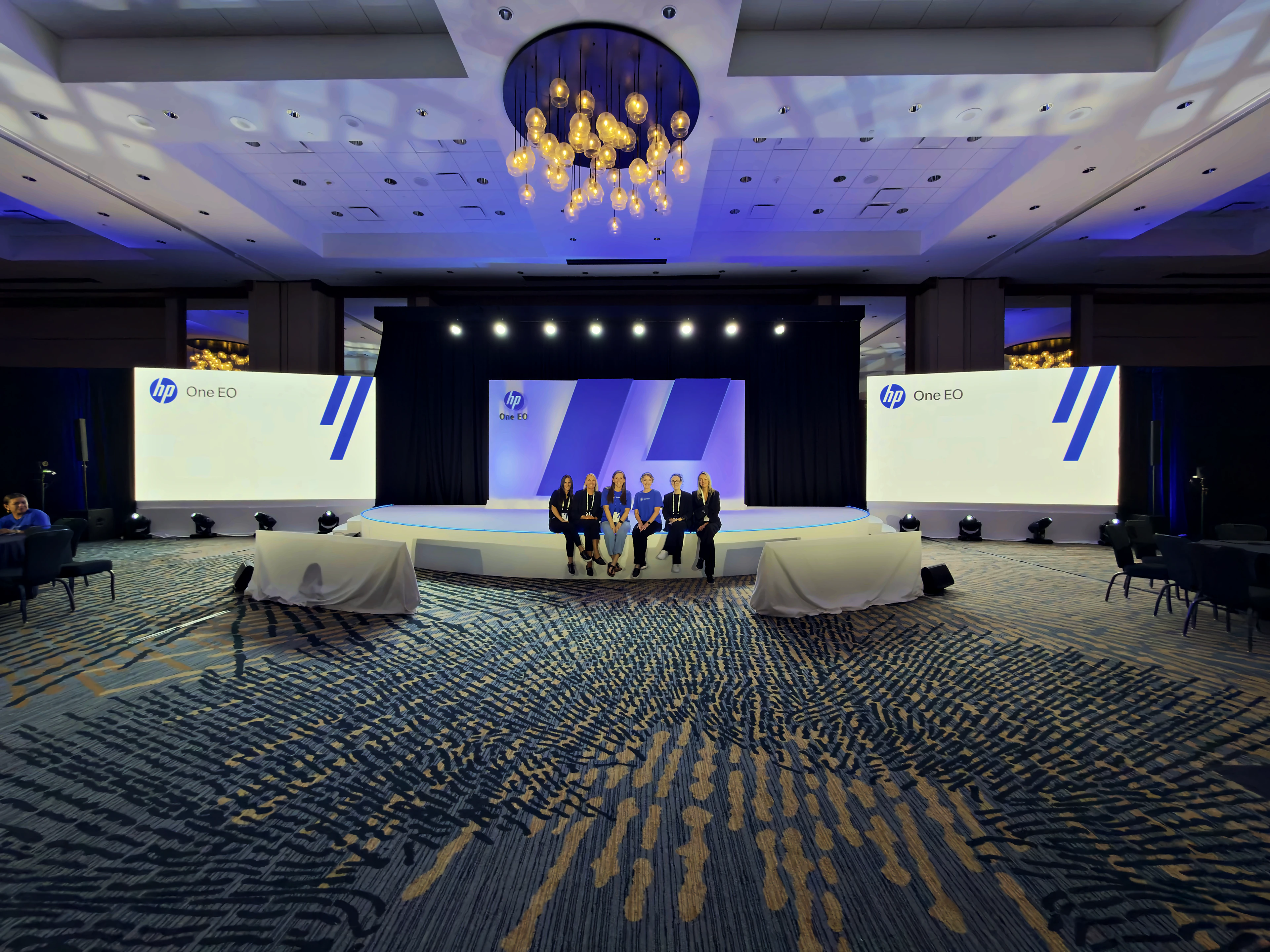 Custom half-circle stage and fabricated scenic wall carrying one event identity across stage and screens