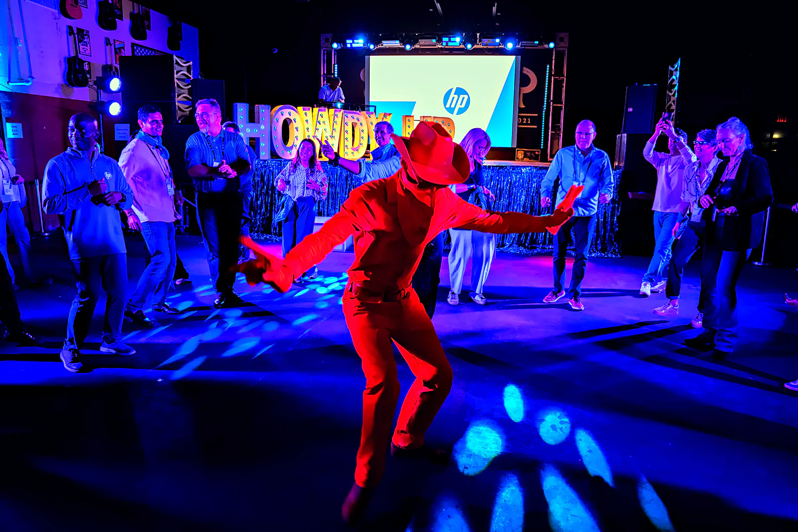 Red-suited performer working the crowd beneath the Howdy marquee at the Neon Cowboy offsite