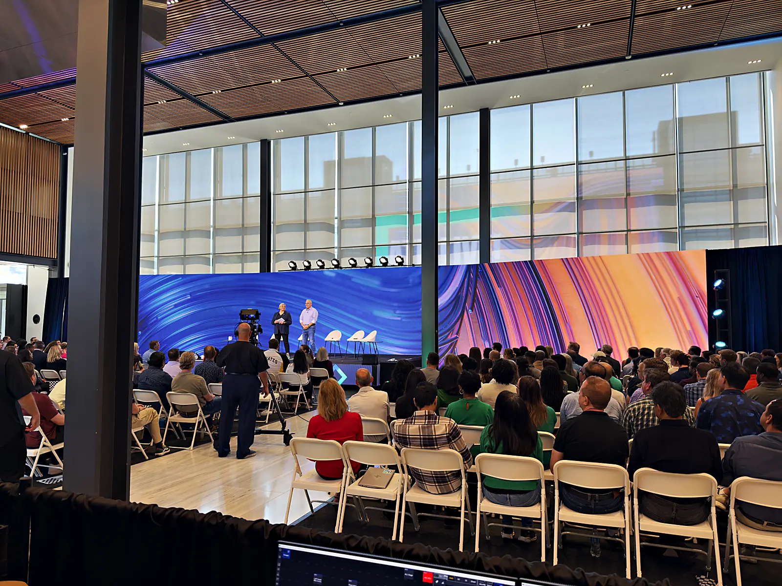 The live audience watching a panel discussion against the sweeping LED wall