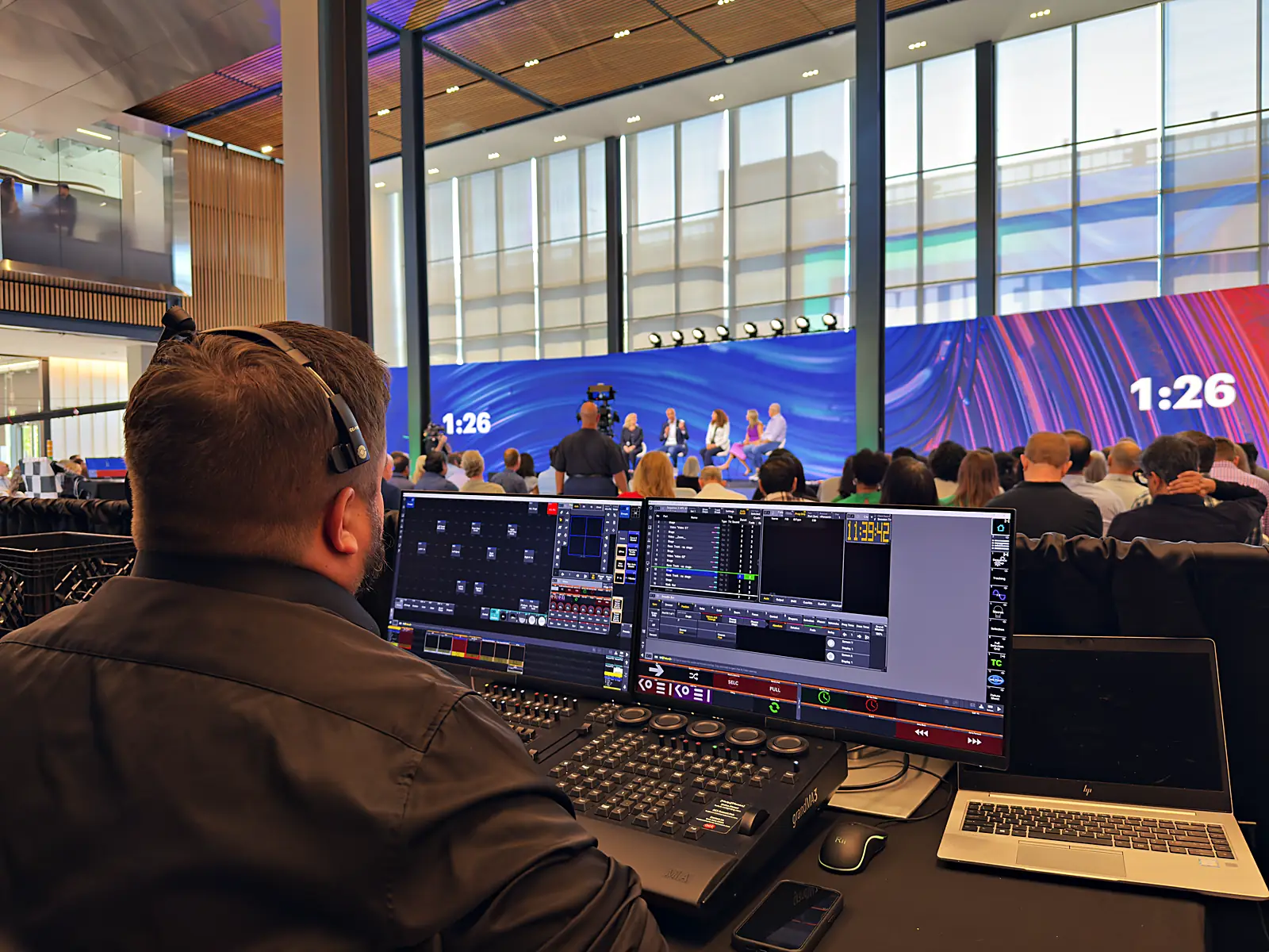 Operator at the lighting console with the live panel, countdown, and full audience beyond