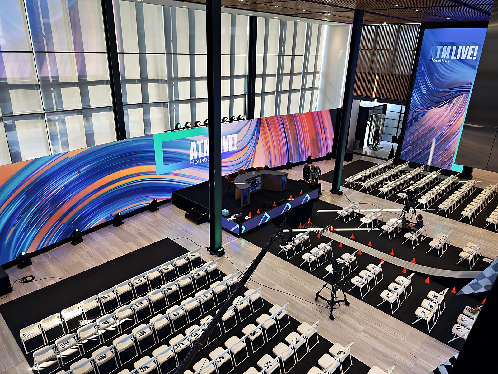 Elevated wide of the full ATM Live room: curved LED wrap, theater seating, and camera jib