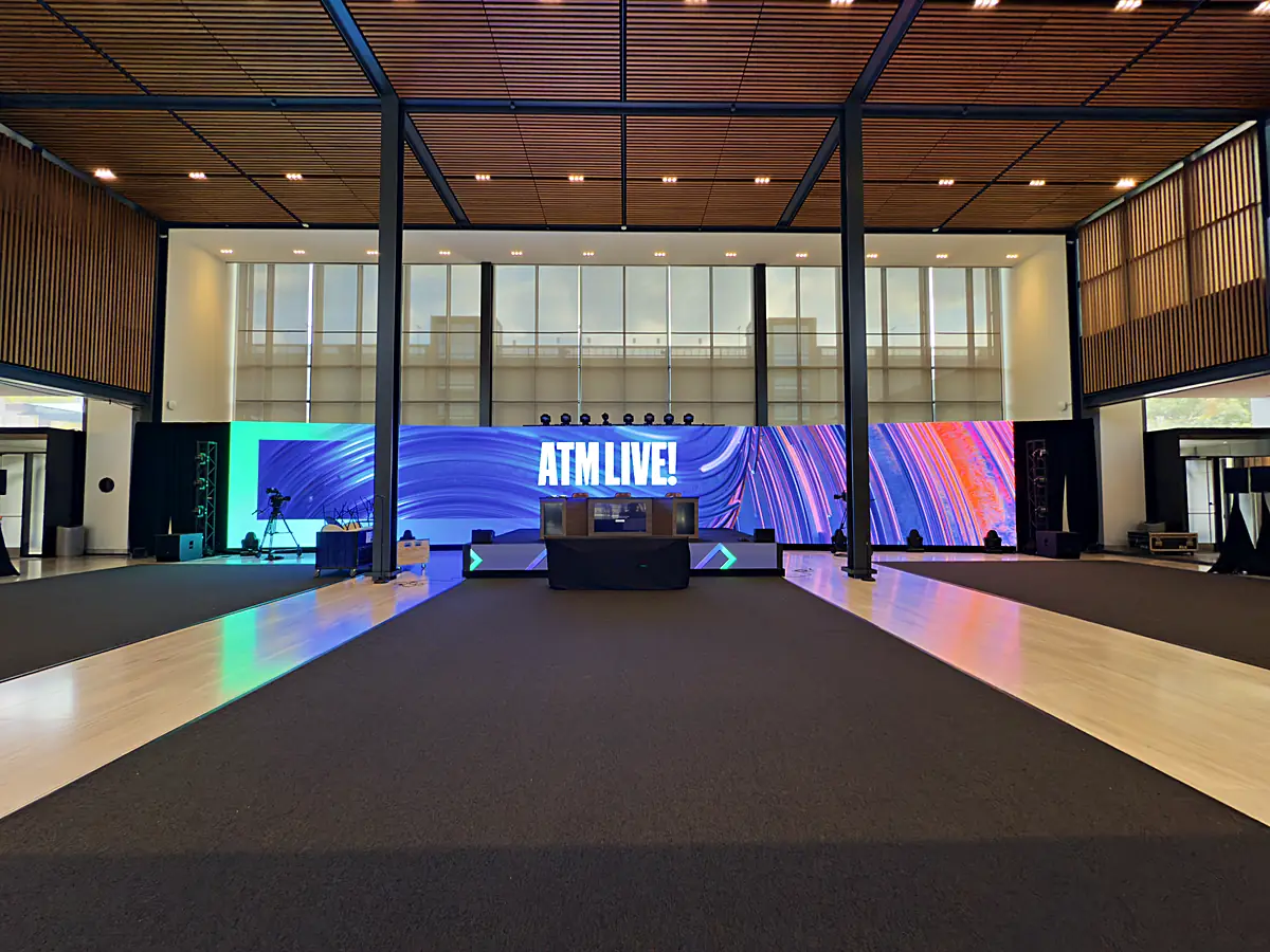 The ATM Live branded runway and anchor desk under a panoramic LED wall