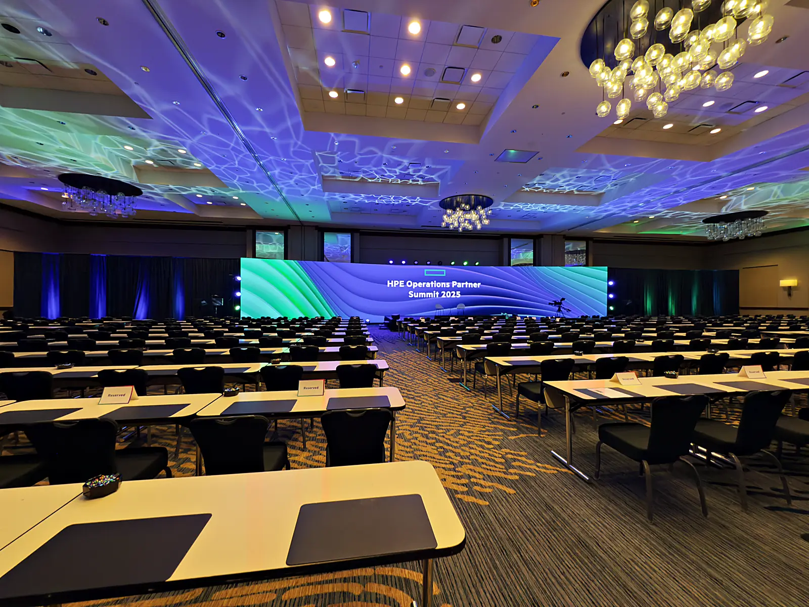 The curved seamless LED wall lit with brand graphics across the empty ballroom before doors