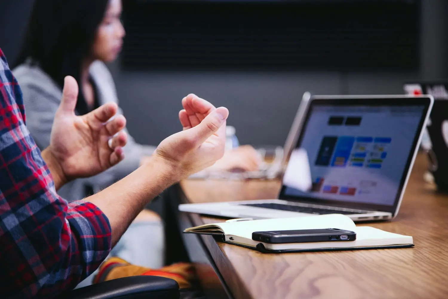 Hands raised in discussion over a laptop during a production vendor meeting.
