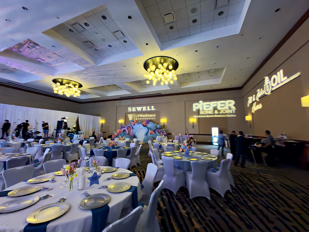 A fundraising gala room at scale with welcome wall and gobo lighting